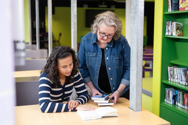 Leraar met leerling in schoolbieb