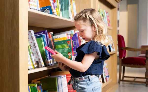 meisje met boek in bibliotheek