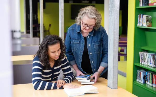meisje en docent in schoolbibliotheek